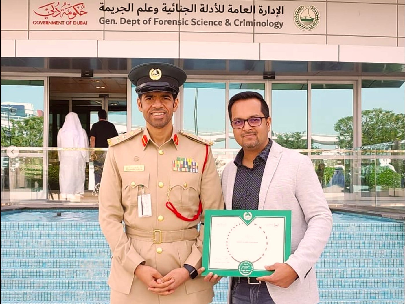 Ramesh holding the CX Champion certificate beside a Dubai Police officer